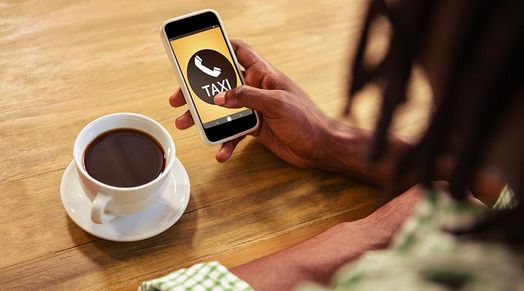 Kaffe und Handy mit Taxiapp